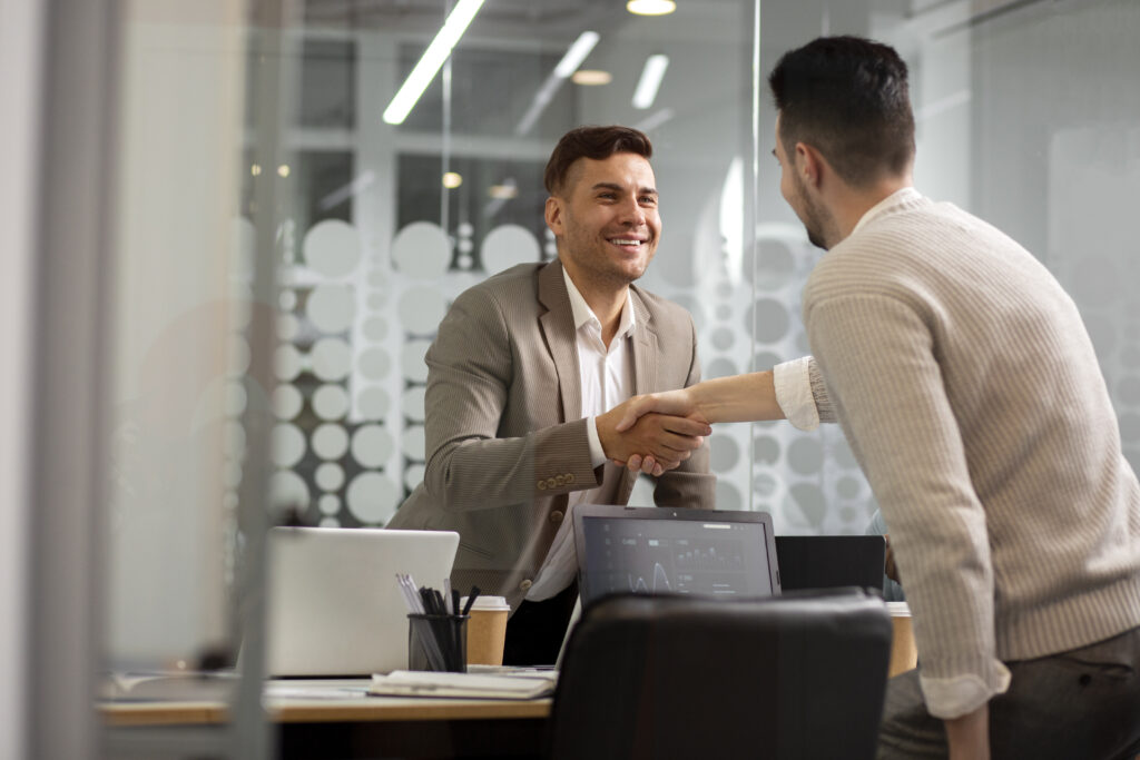 Mortgage broker meeting clients, shaking hands across a desk in a modern office, representing home loans and finance services in NSW and QLD by Kesh Finance Solutions.